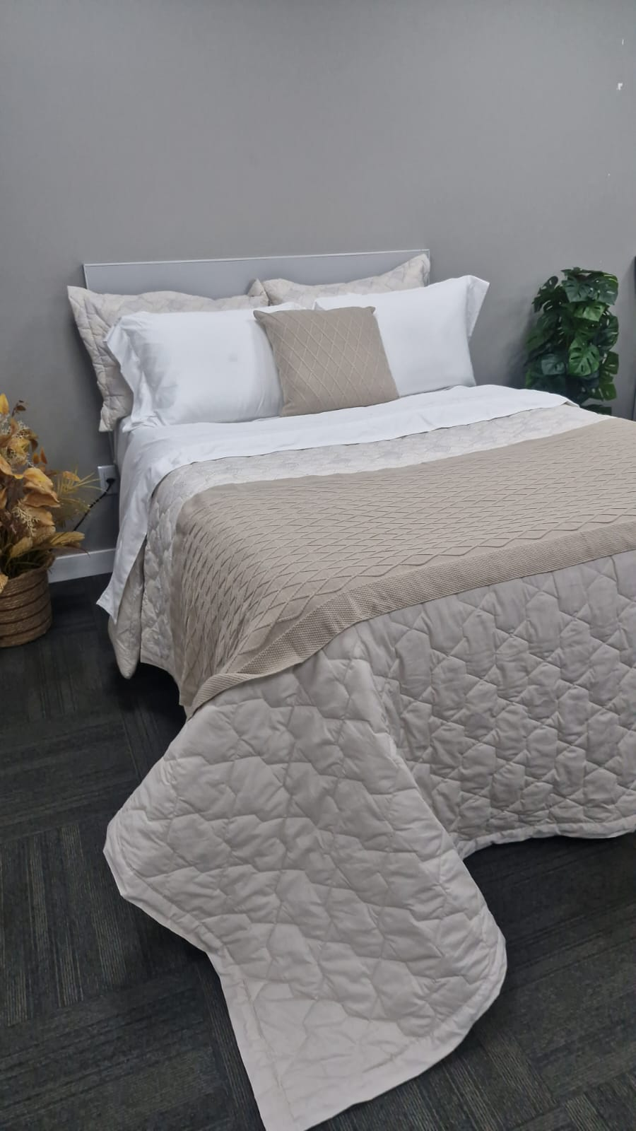 Cama com colcha bege e jogo de cama branco